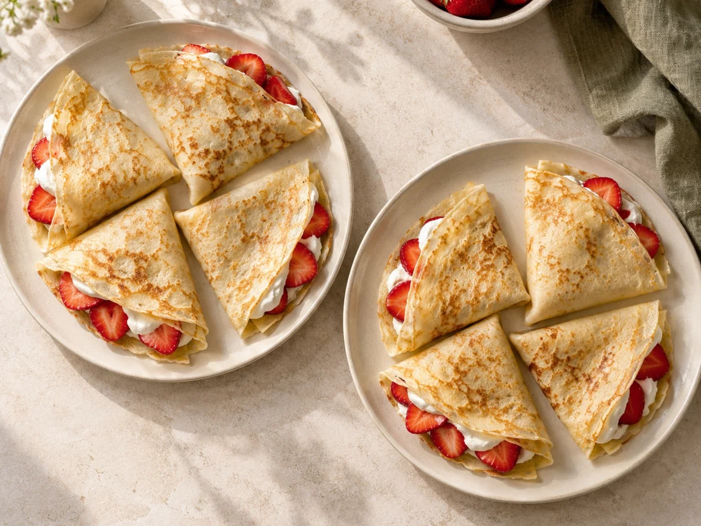 Eight thin folded strawberry and yogurt crepes divided between two plates